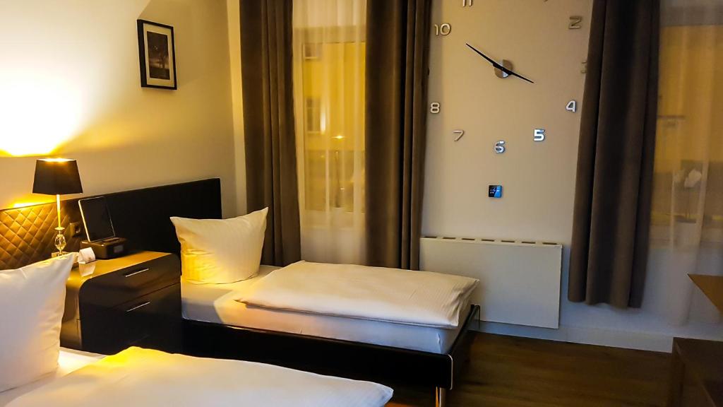 莱比锡莱比锡伍尔夫公寓的酒店客房设有两张床和墙上的时钟。