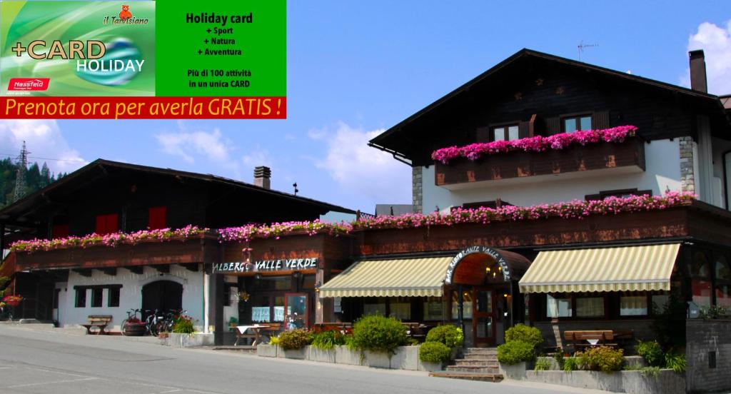 塔尔维西奥Hotel Valle Verde - Rent Ski & Bike的花朵边的建筑
