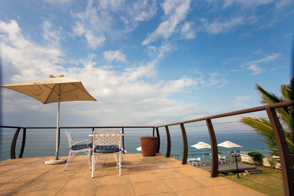 阿曼济姆托蒂Ocean Hideaway Bed and Breakfast的阳台配有桌子和遮阳伞,享有海景。