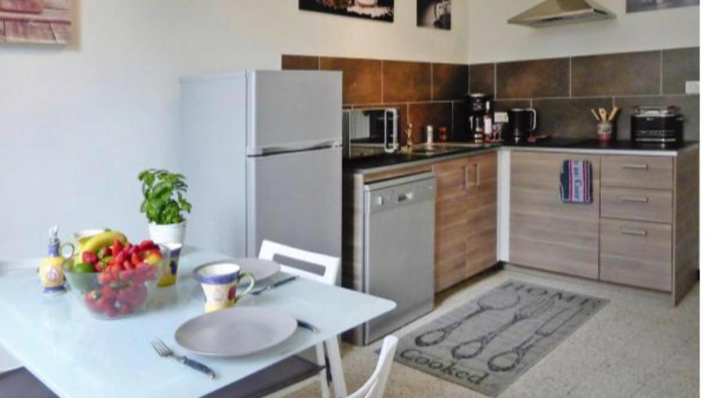 阿尔勒Duplex meublé face aux arènes d'ARLES的厨房配有桌子和白色冰箱。