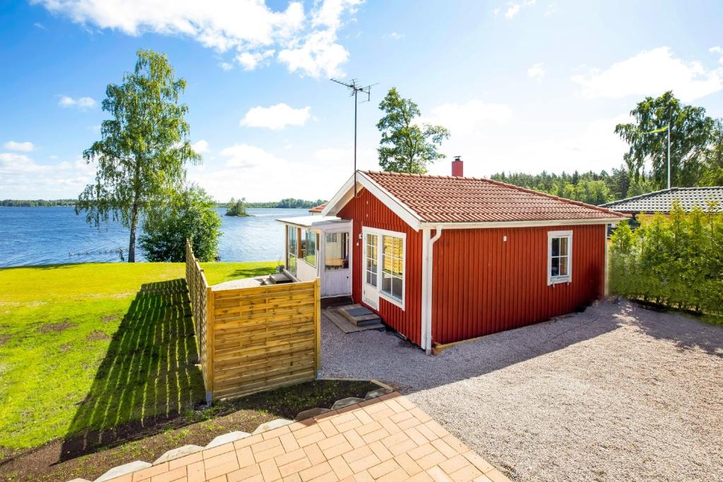 BjörköbyHoliday Lakefront house的水体旁有栅栏的红棚
