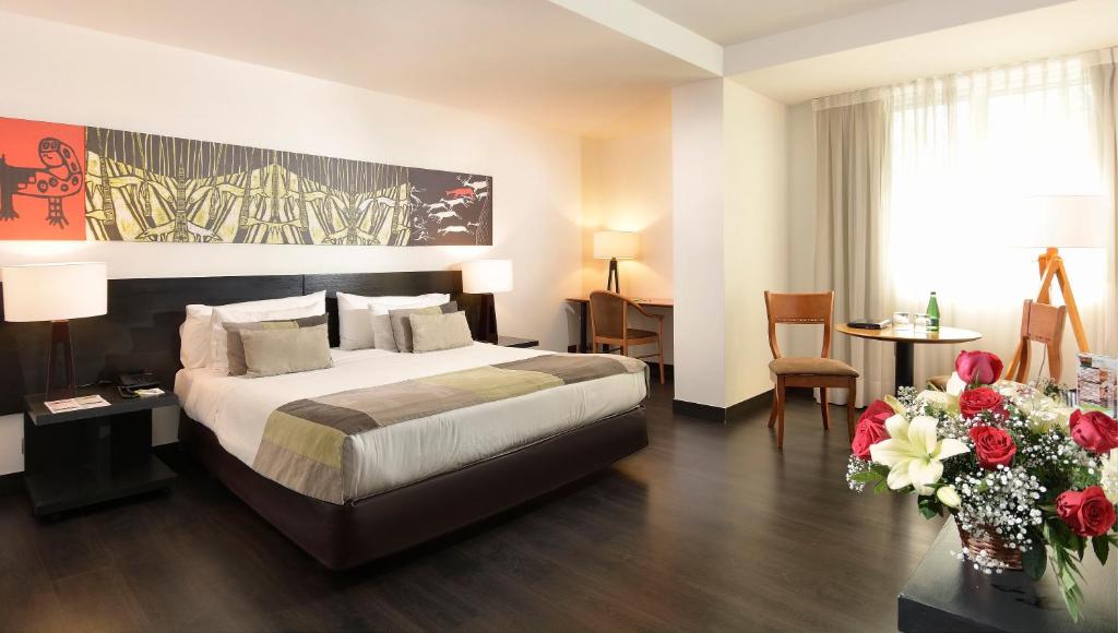 圣地亚哥普罗维登斯欧洲电信酒店的配有床和鲜花桌的酒店客房