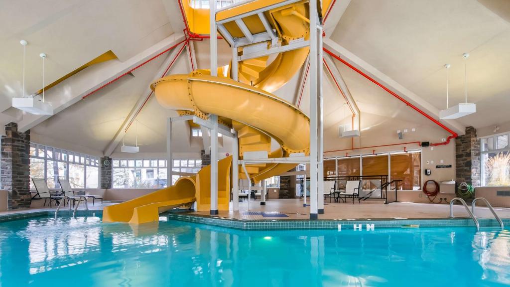 坎莫尔Pocaterra Inn & Waterslide的一座建筑中带有黄色滑梯的游泳池