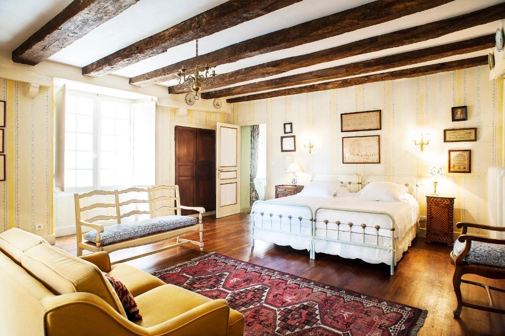 萨尔拉拉卡内达Appartements Les Suites sarladaises的一间卧室配有一张床、一张沙发和一把椅子