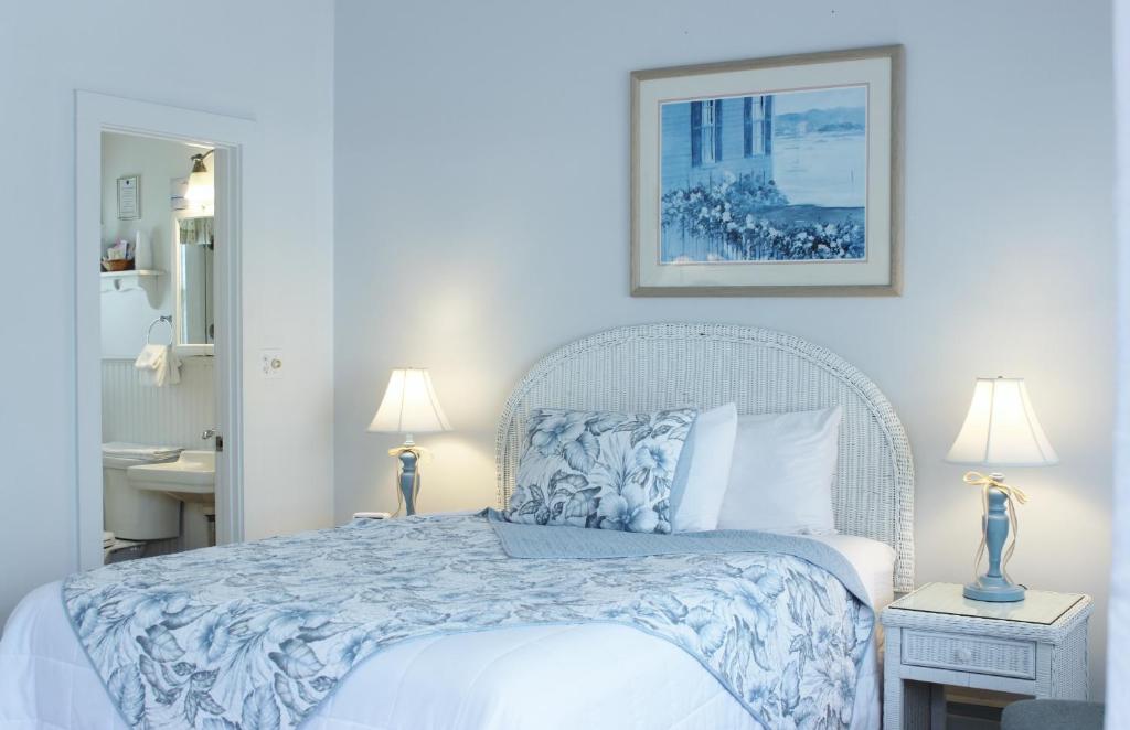 法尔茅斯红马宾馆的一间卧室配有一张带蓝色和白色床单的床。