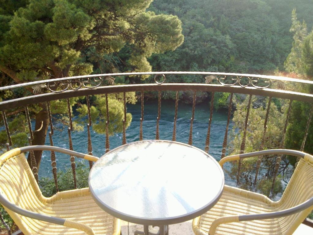 莫斯塔尔维拉公园酒店的阳台配有桌椅,享有水景