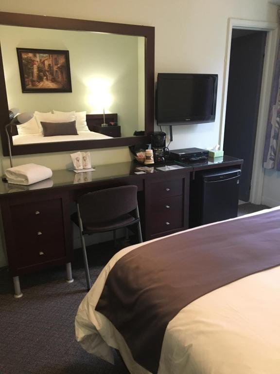 萨格奈中央城镇宾馆的酒店客房配有一张桌子、一张床和一台电视