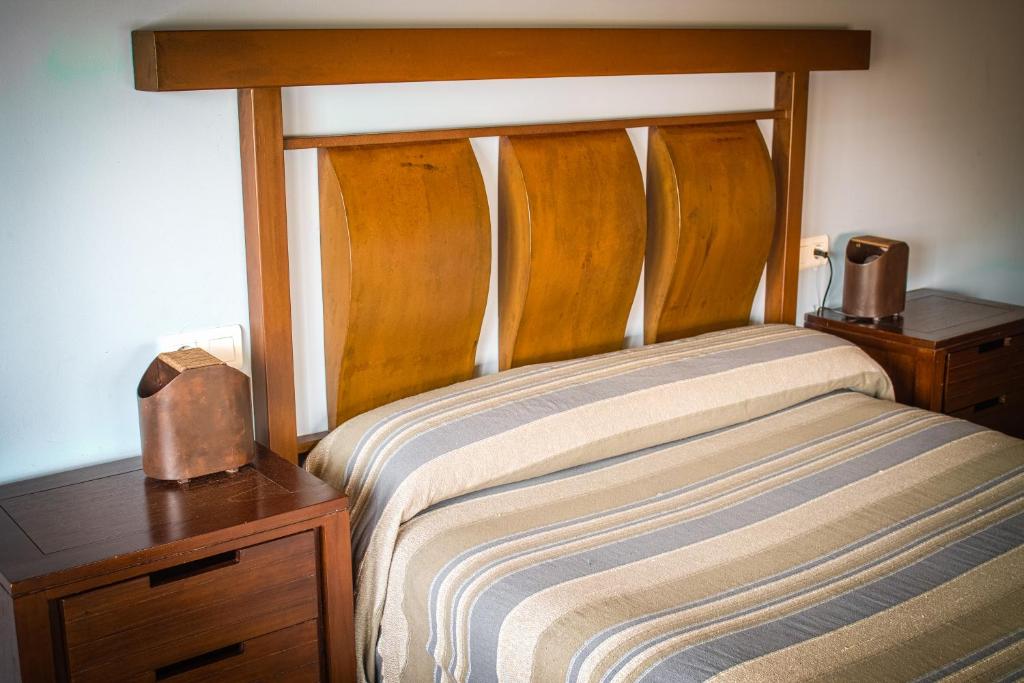 GalveHotel Rural Casa La Era的一间卧室配有一张带木制床头板和床头柜的床。