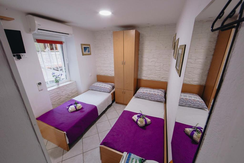 斯普利特Old Town Apartment Split的一间设有两张紫色靠垫的床的房间
