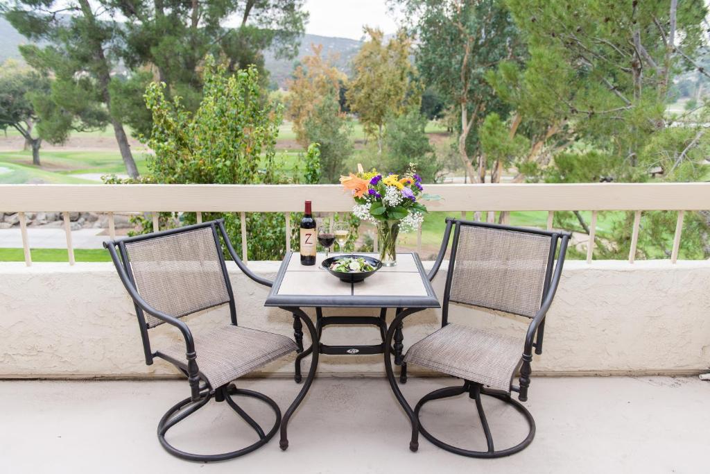 拉莫纳圣维森特高尔夫度假酒店的阳台上配有一张桌子和两把椅子,并提供一瓶葡萄酒