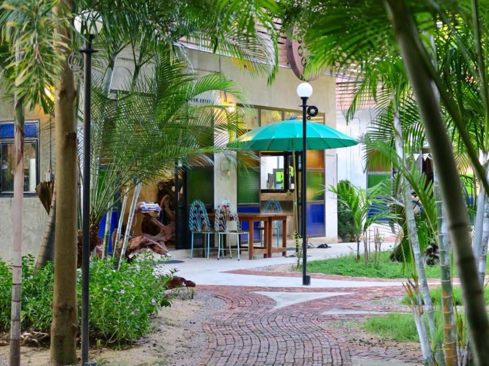 美索The Picturebook Guesthouse的棕榈树建筑前的绿色遮阳伞