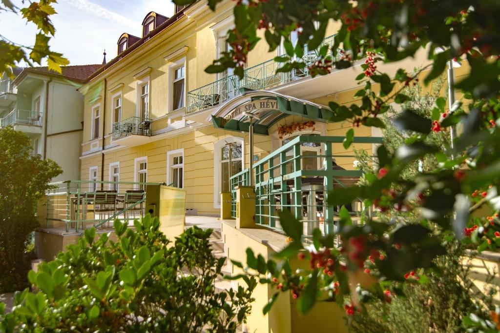 赫维兹Hotel Spa Hévíz的一座带阳台和树木的大型黄色建筑