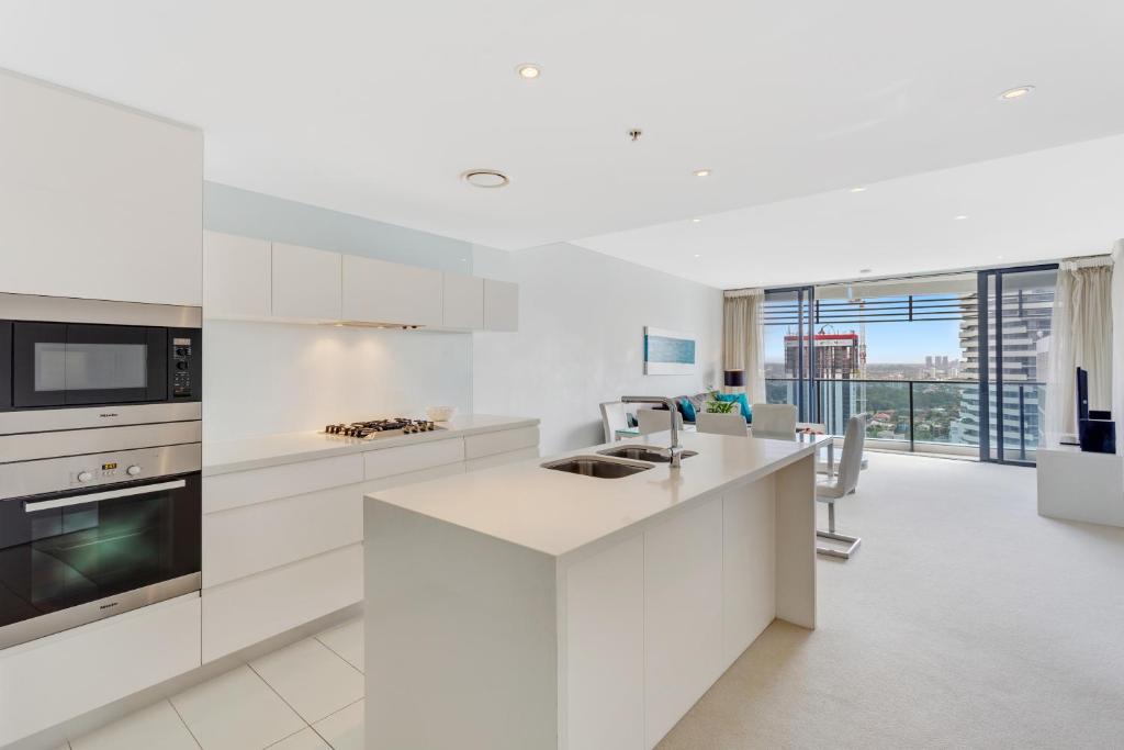 黄金海岸Oracle - 5 Star Luxury - Level 25的一间厨房,配有白色的橱柜和大窗户