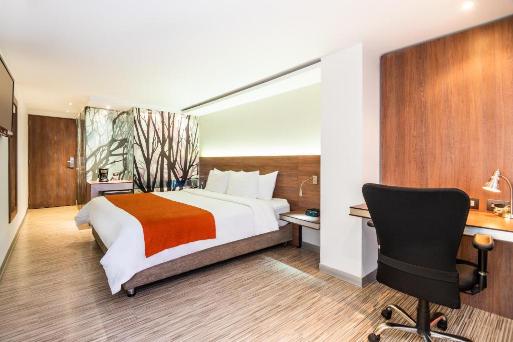 波哥大SHG Bogotá 100 Design Hotel的一间卧室配有一张床、一张桌子和一把椅子