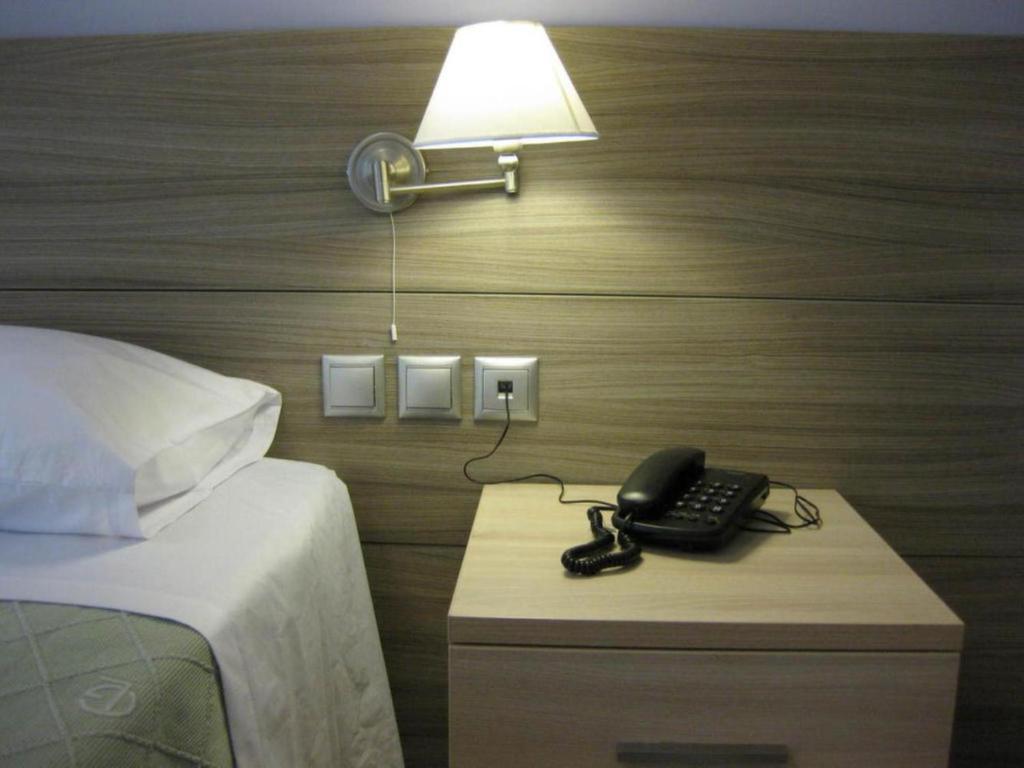 卡梅纳维洛拉亚历山德罗斯公寓式酒店的床头的床头柜上的电话