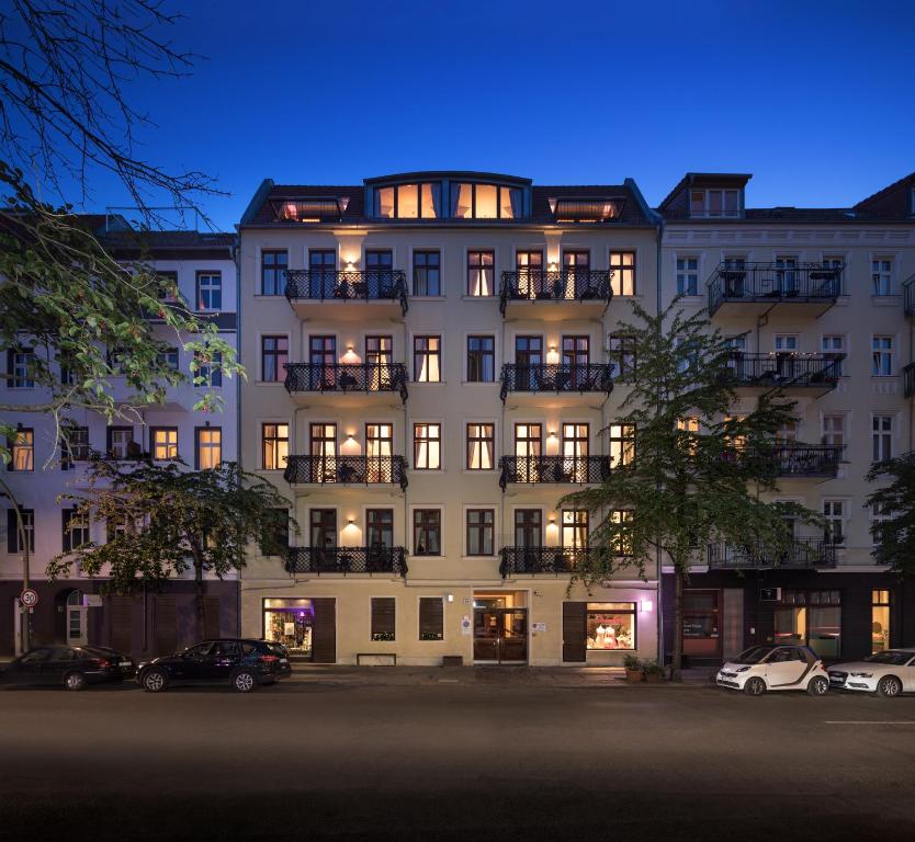 柏林鲁克斯依斯公寓的一座白色的大建筑,前面有汽车停放