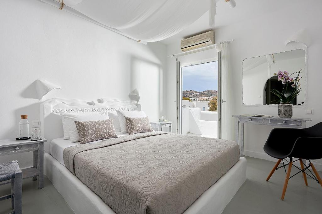 阿达玛斯米洛斯酒店的白色卧室配有床和镜子
