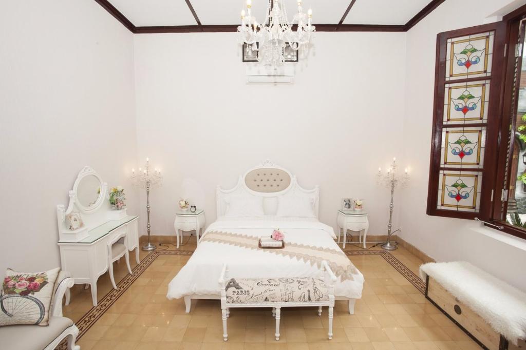 玛琅Huis Van Gustafine Floor 1的卧室配有白色的床和吊灯。