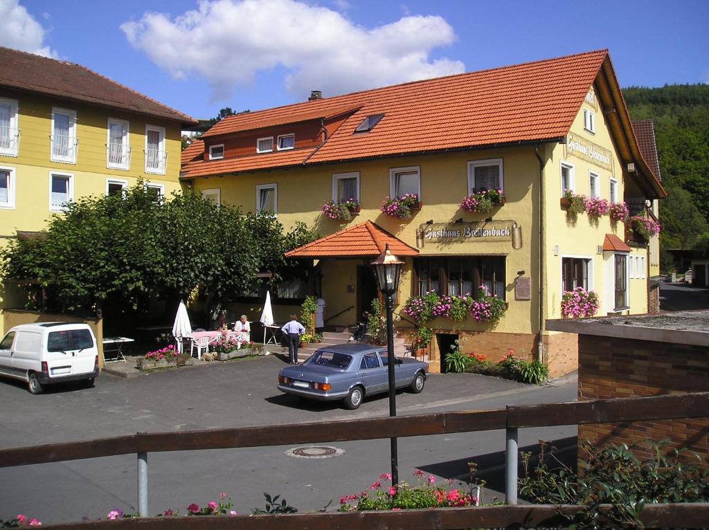 巴特布吕克瑙Gasthaus Breitenbach的停在黄色建筑前面的蓝色汽车