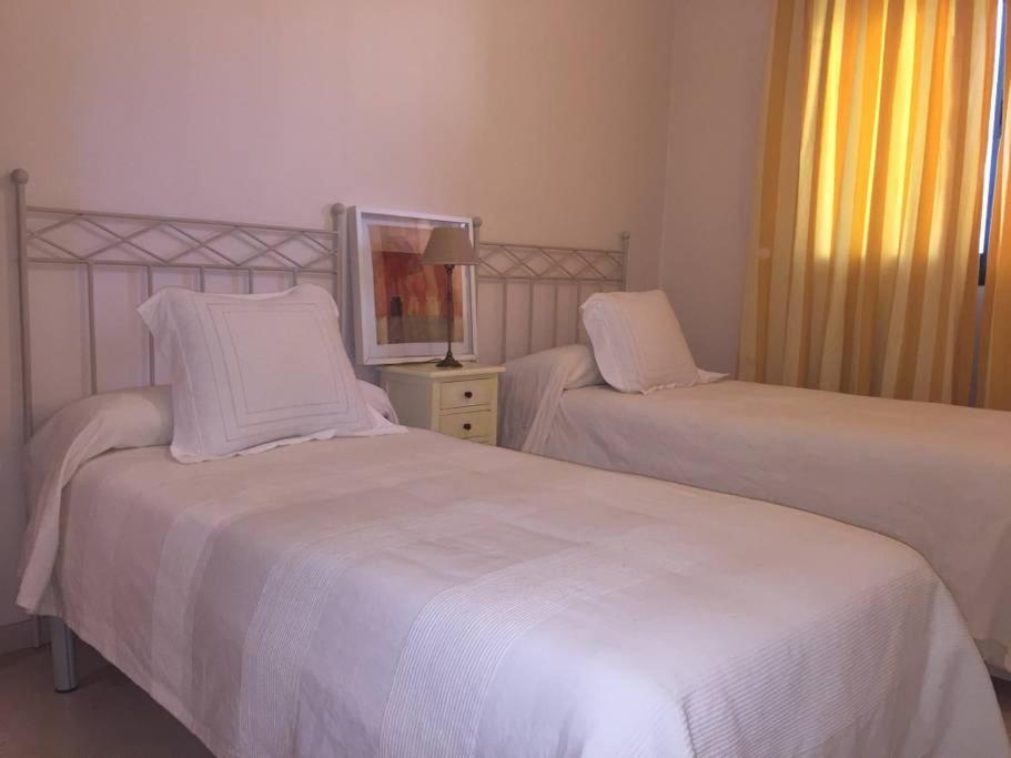 格拉纳达Conjunto Altos de Vista Nevada,nº11,portal 7,1ºA.的一间卧室配有两张带白色床单和镜子的床