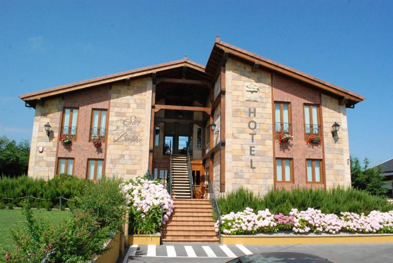 Elechas巴伊亚畔公寓式酒店的砖砌的建筑,前面有楼梯和鲜花