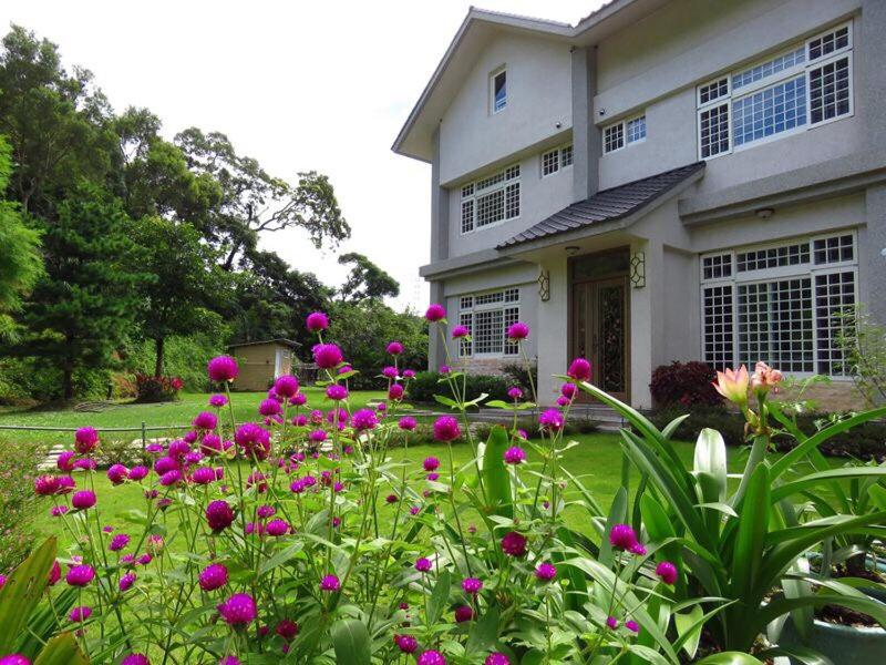 Emei凤姊庄园民宿 的院子前有粉红色花的房子