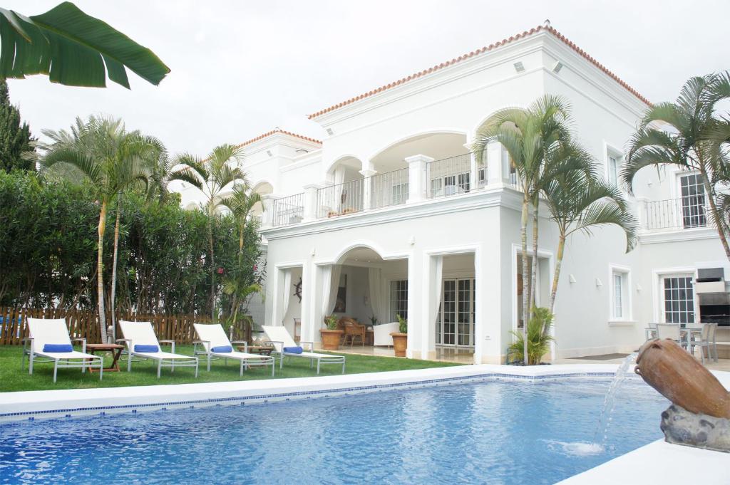 阿德耶Villas Espléndida的白色的房子,设有游泳池和棕榈树
