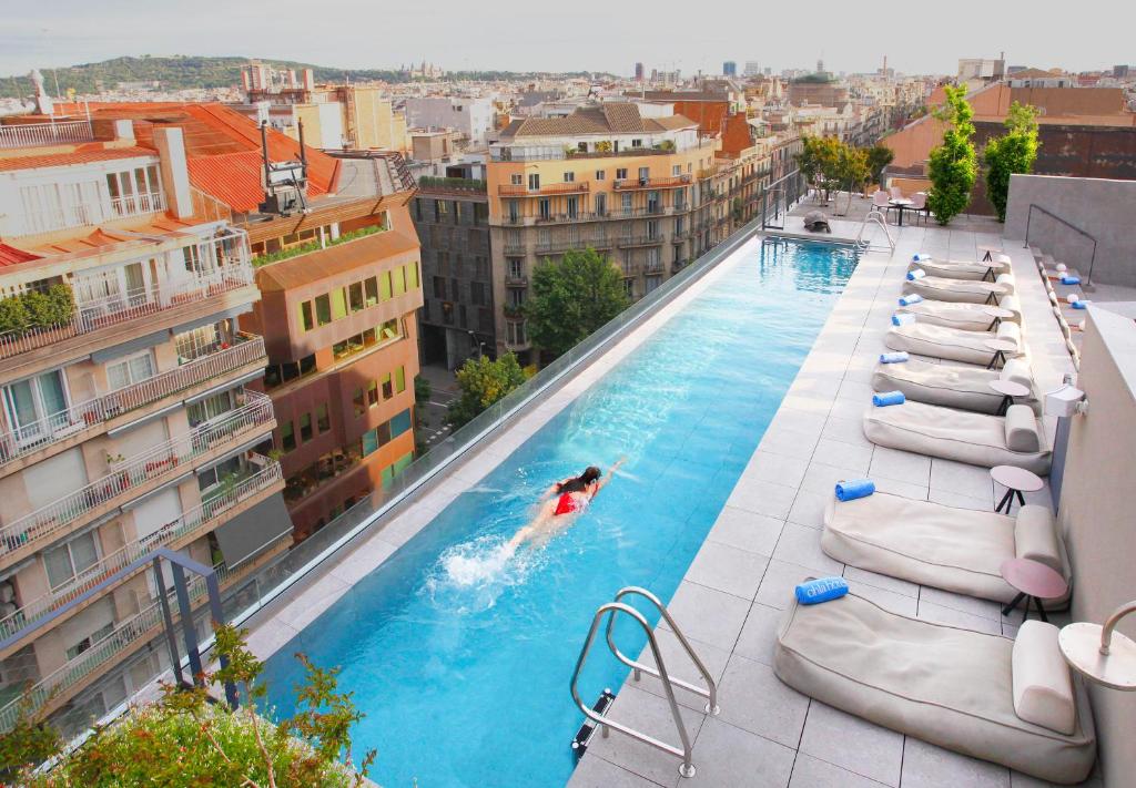巴塞罗那奥拉埃克赞普酒店的在建筑物顶部的游泳池游泳的人