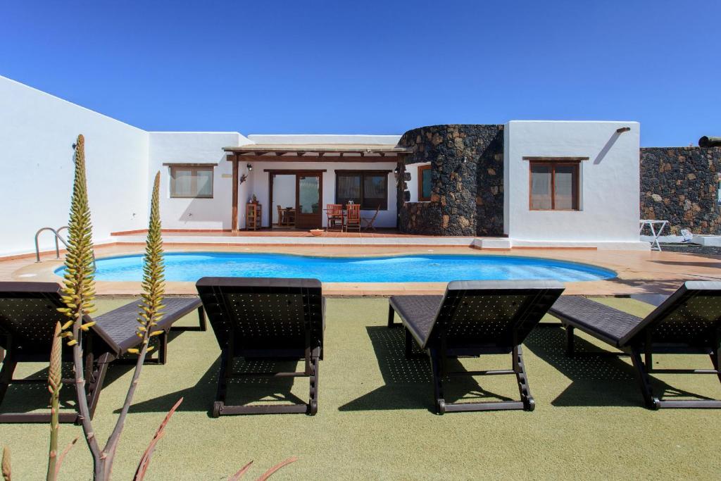 拉奥利瓦Casa MINA的一座带游泳池、椅子和房屋的别墅