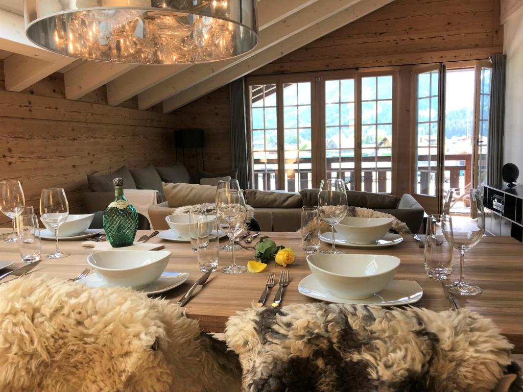 伦克Chalet ELK Lenk的用餐室配有带玻璃杯的木桌