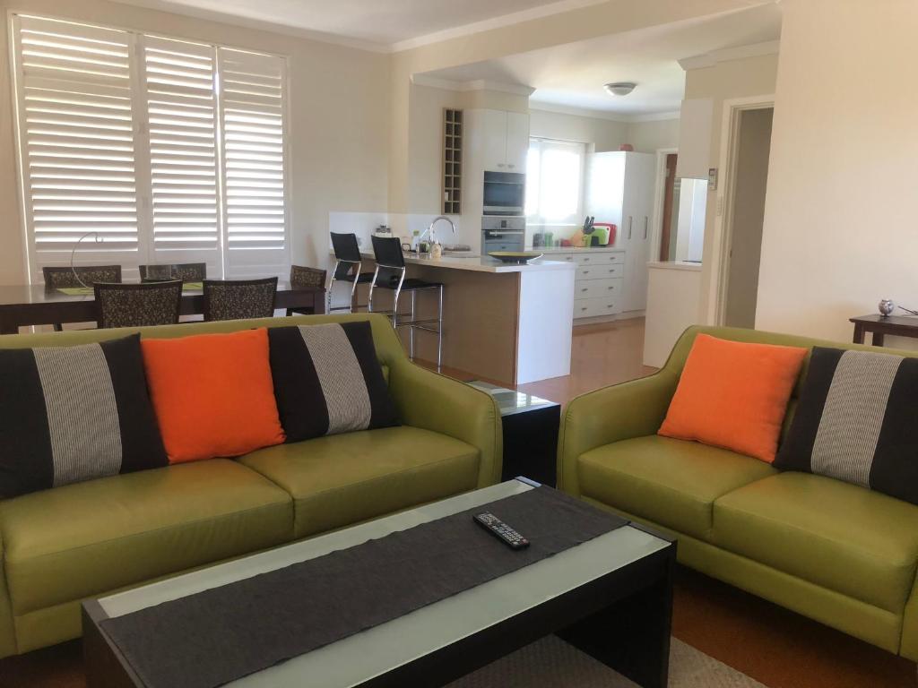 珀斯阿伯克罗斯阿罗拉公寓的一间带两张绿色沙发的客厅和一间厨房