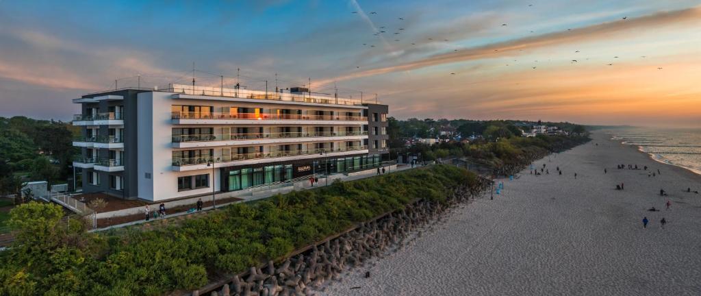 梅尔诺Baltivia Sea Resort的海滩旁的一座建筑,前面的人在海滩前行走