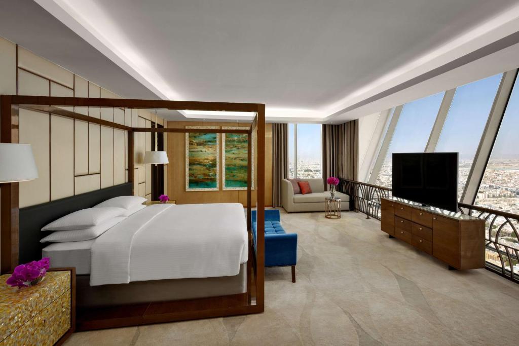 利雅德利雅德奥莱亚凯悦酒店的一间卧室配有一张床、一台电视和一个阳台