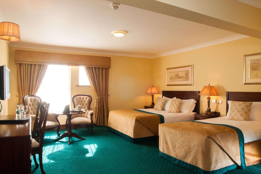 洛赫雷米多克特酒店的酒店客房带两张床和一张桌子以及椅子。