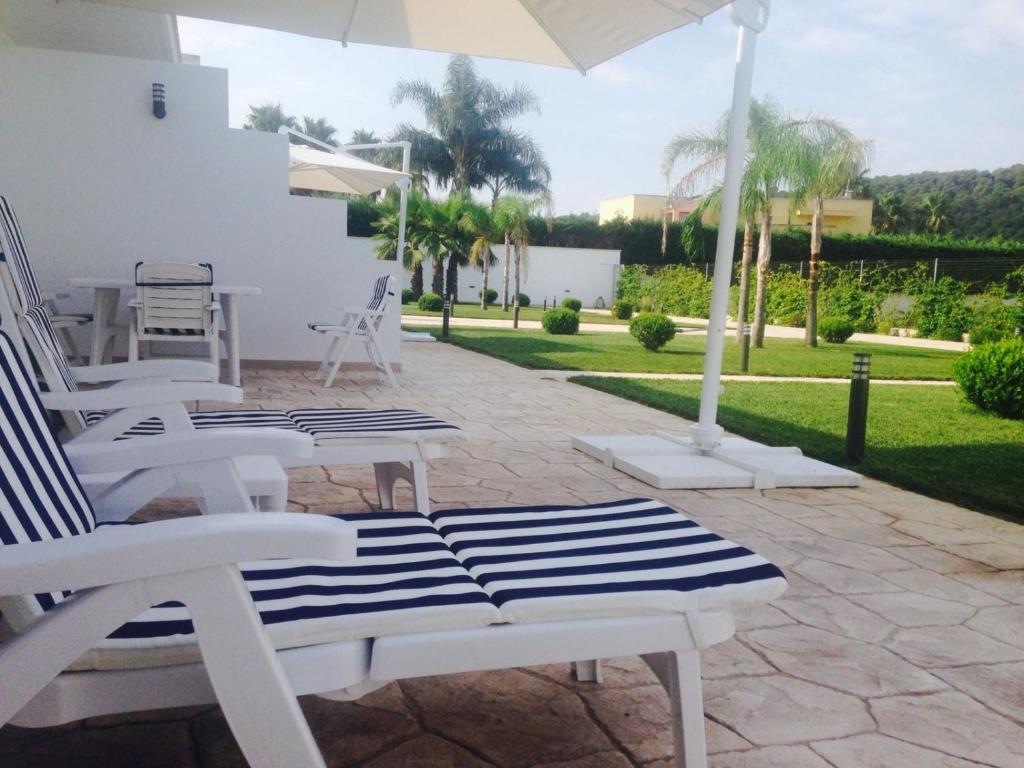 SupersanoDani's residence的庭院配有白色的椅子和遮阳伞。