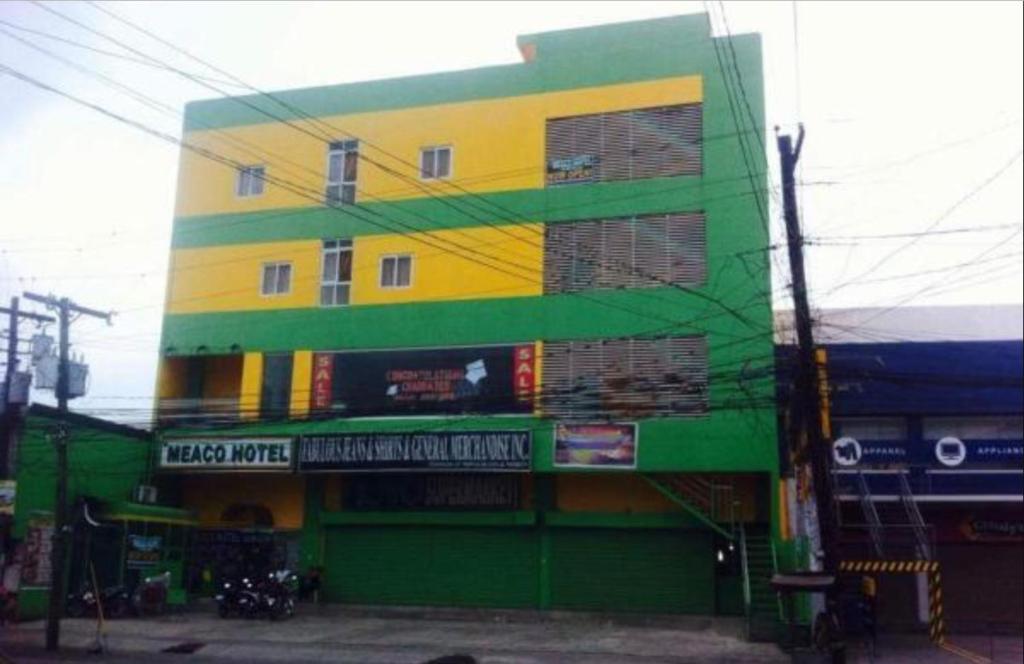 SolanoMeaco Hotel - Solano的街道上一座黄色和绿色的建筑