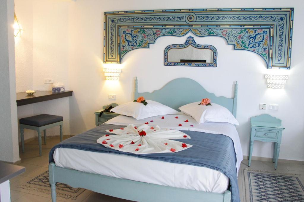 哈马马特克拉酒店的卧室配有蓝色和白色的床,床上有鲜花