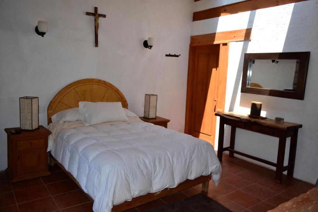Amanalco de BecerraHotel Boutique El Campirano的卧室配有一张床,墙上有十字架