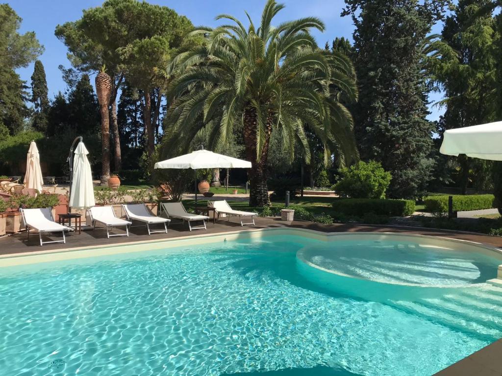 阿布鲁齐的罗塞托罗塞拉度假别墅酒店的一个带椅子和遮阳伞的游泳池以及棕榈树