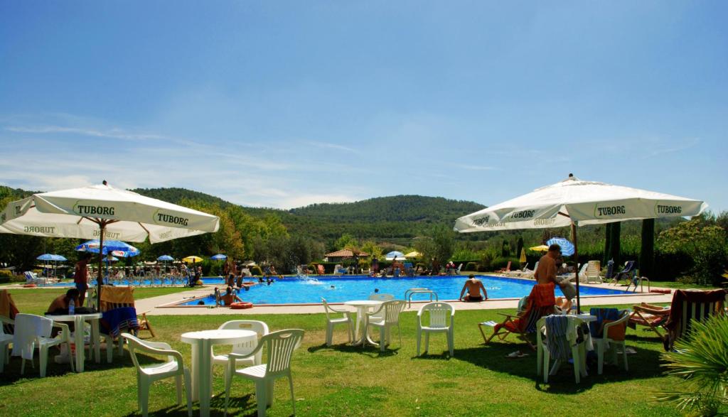 博尔塞纳丽都野营村度假酒店的一组椅子和遮阳伞,位于游泳池旁