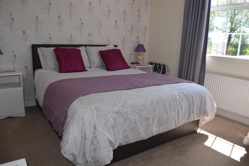 BagenalstownOrchard Grove bed & breakfast R21RC58的一间卧室配有一张带紫色和白色床单的床和窗户。
