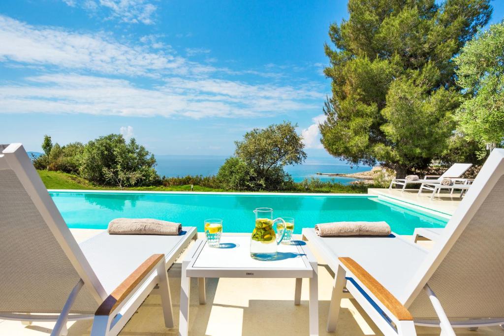 尼基季A&A Luxury Beach Villas的游泳池畔的一张桌子和两把椅子