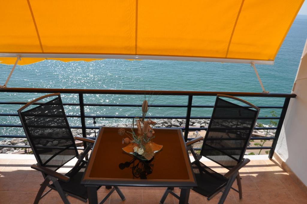 多列毛利诺斯Studio Vue Mer的阳台配有一张桌子和两把椅子,享有海景