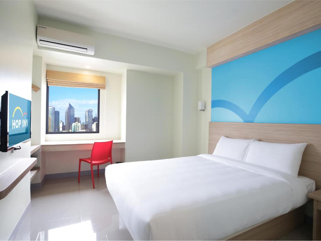 马尼拉Hop Inn Hotel Alabang Manila的卧室配有白色的床和红色椅子