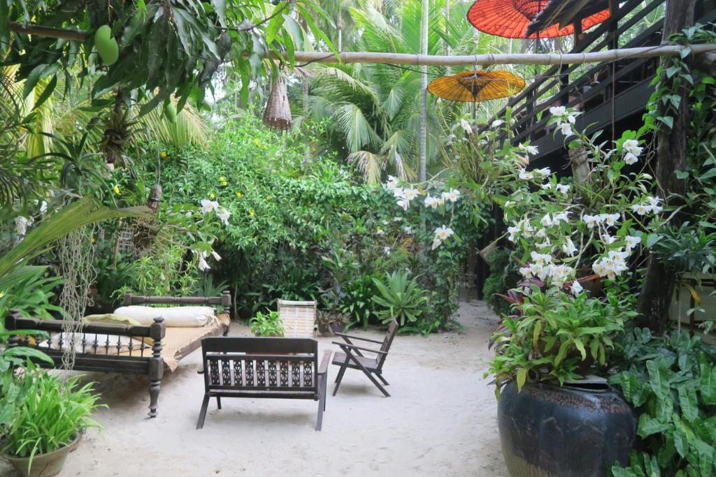 额布里Kipling's Bay Guest house的一个带长椅和植物的花园以及一把遮阳伞