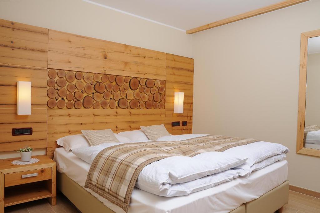 梅扎纳Residence Marisol Camere & Appartamenti - Mezzana Centre的一间卧室设有一张带木墙的大床