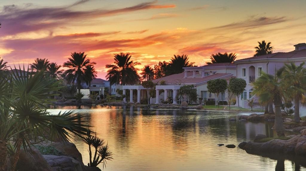 阿可贺巴Sunset Beach Resort Marina & Spa的日落时分拥有湖泊和棕榈树的度假胜地