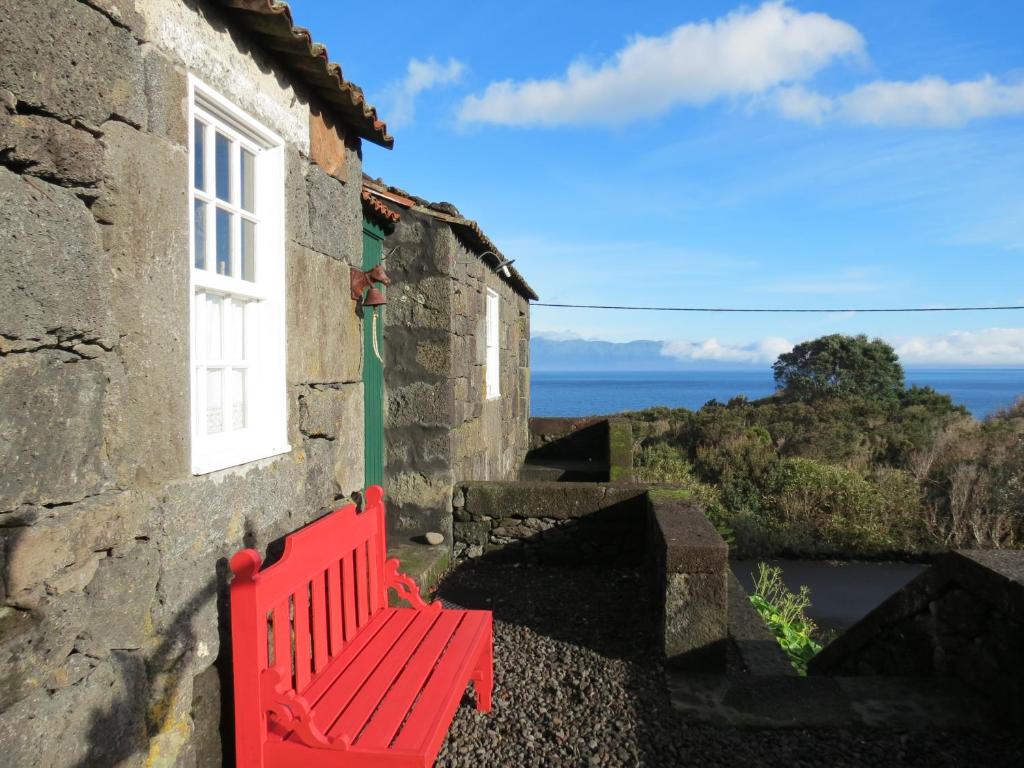 Terra AltaCasa Adega Alto do Passinho的坐在大楼一侧的红色长凳