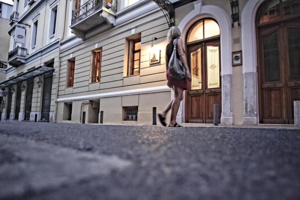 雅典雅典城市瑟科斯酒店的走在建筑物前的街道上的女人