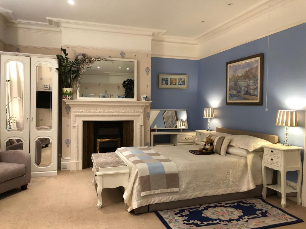 利特尔Arun Sands Rooms的蓝色卧室设有一张床和一个壁炉